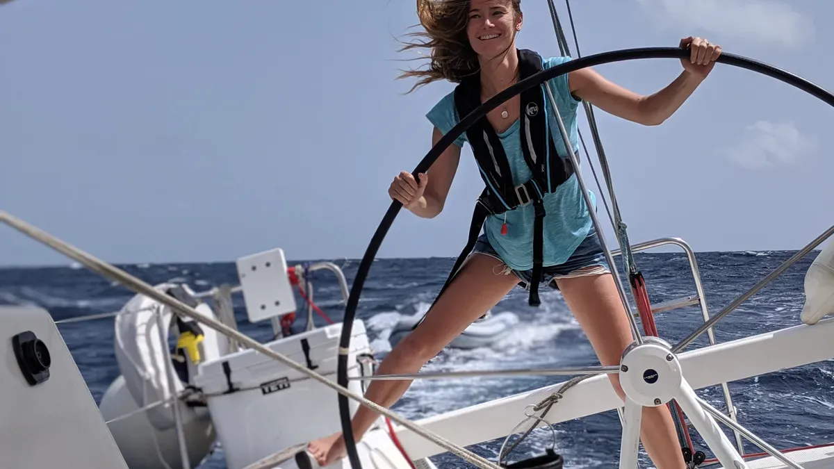 A student at the helm of a heeling sailboat in the trade winds