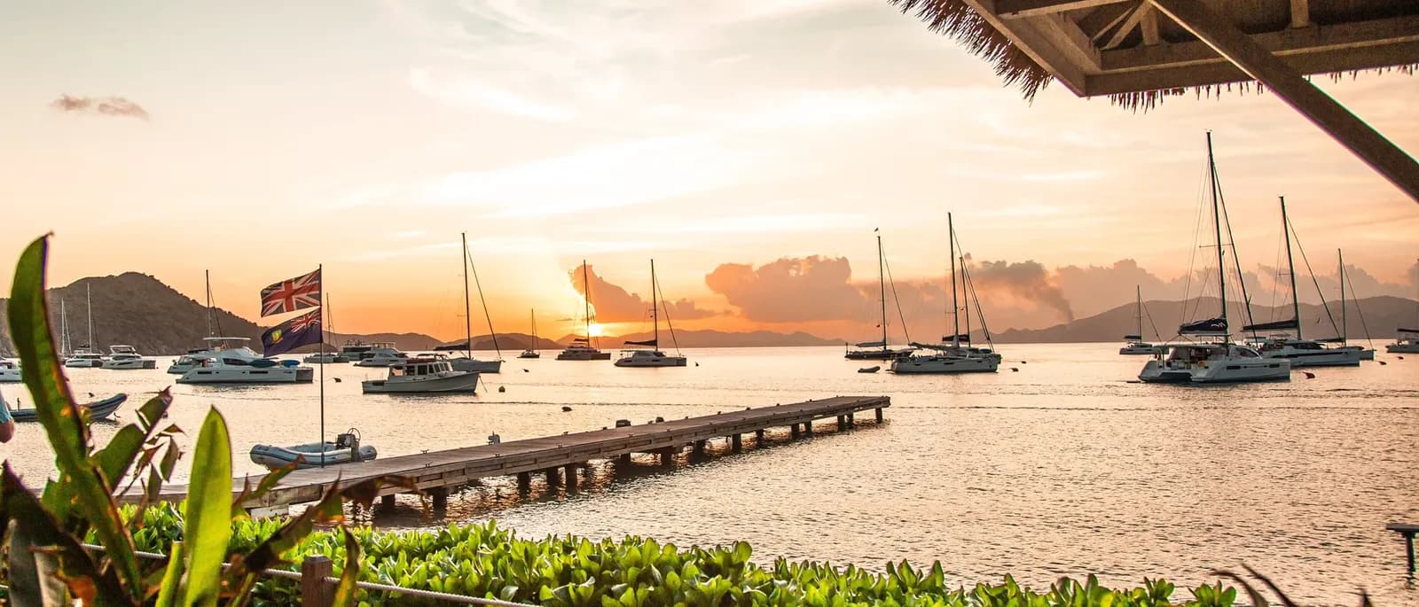 Sunset over yachts at anchor, seen from a beach bar dock