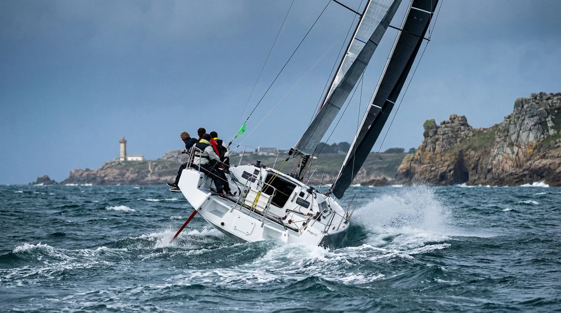 Sailing yacht navigating the dramatic Brittany coastline with pink granite cliffs