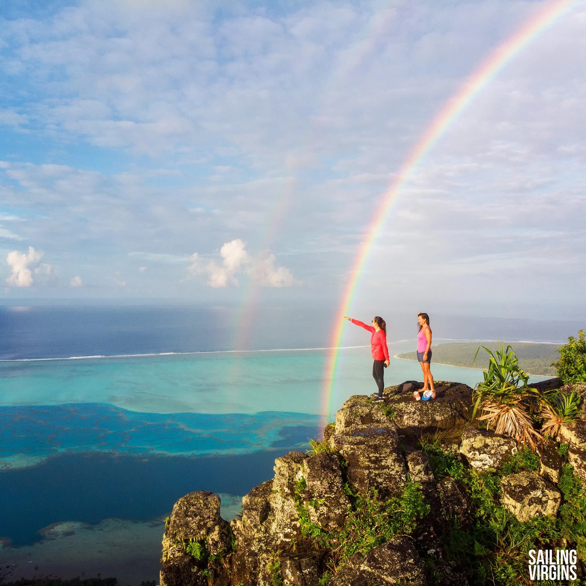 Double rainbow over cliff viewpoint with turquoise sea