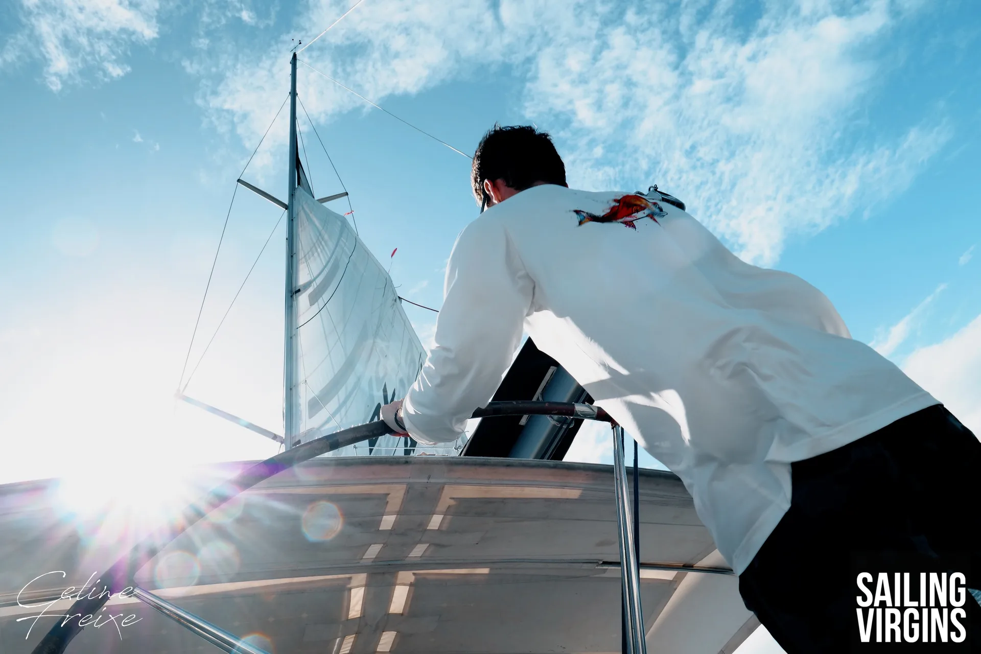 Hoisting sail with sunburst behind