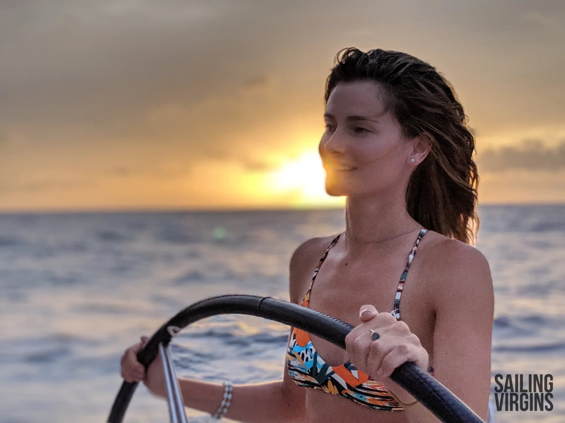 Student helming at sunset