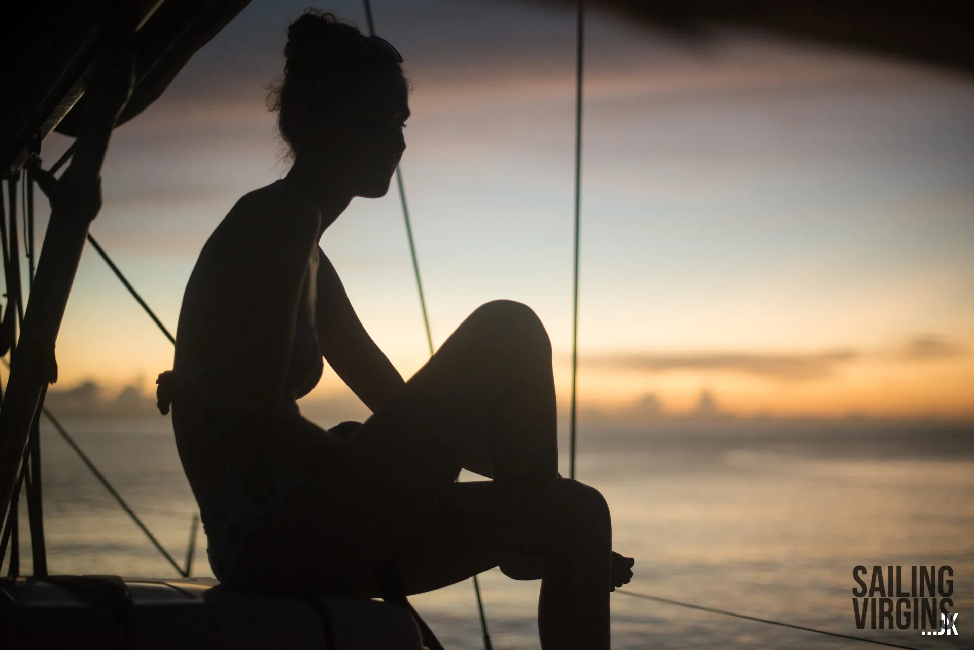 Silhouette sitting on rigging at sunset