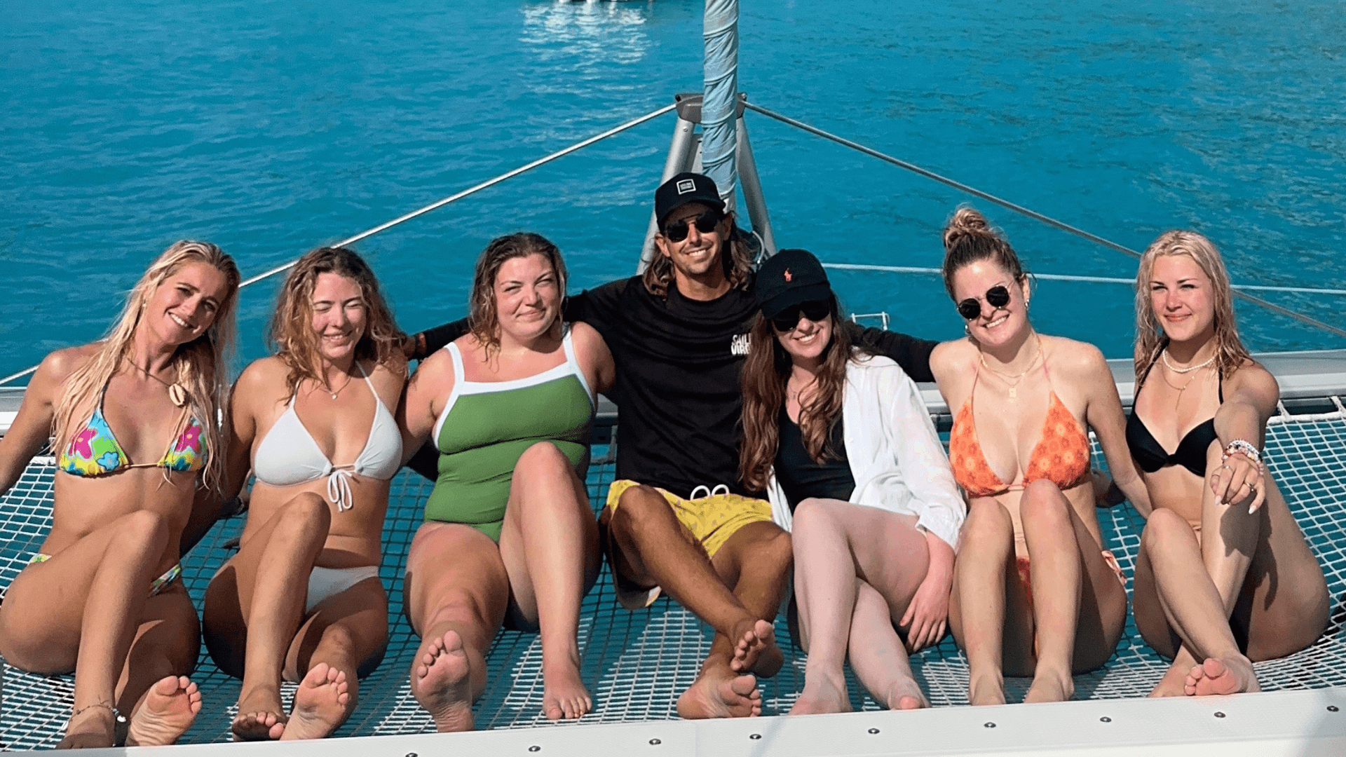 Sailing students relaxing on a catamaran deck in crystal clear Caribbean waters
