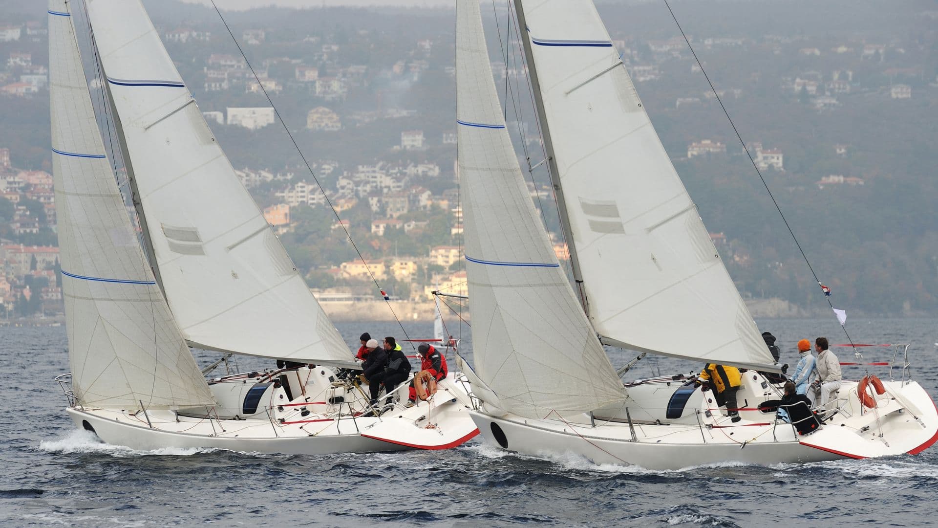 Racing yacht heeled over with colorful spinnaker flying, crew hiking out during competitive sailing