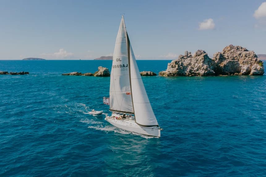 Yacht sailing along dramatic coastline